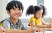 Photo of students smiling at desks to represent 2022 state assessment result score release