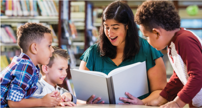 A teacher reading to three young kids. 